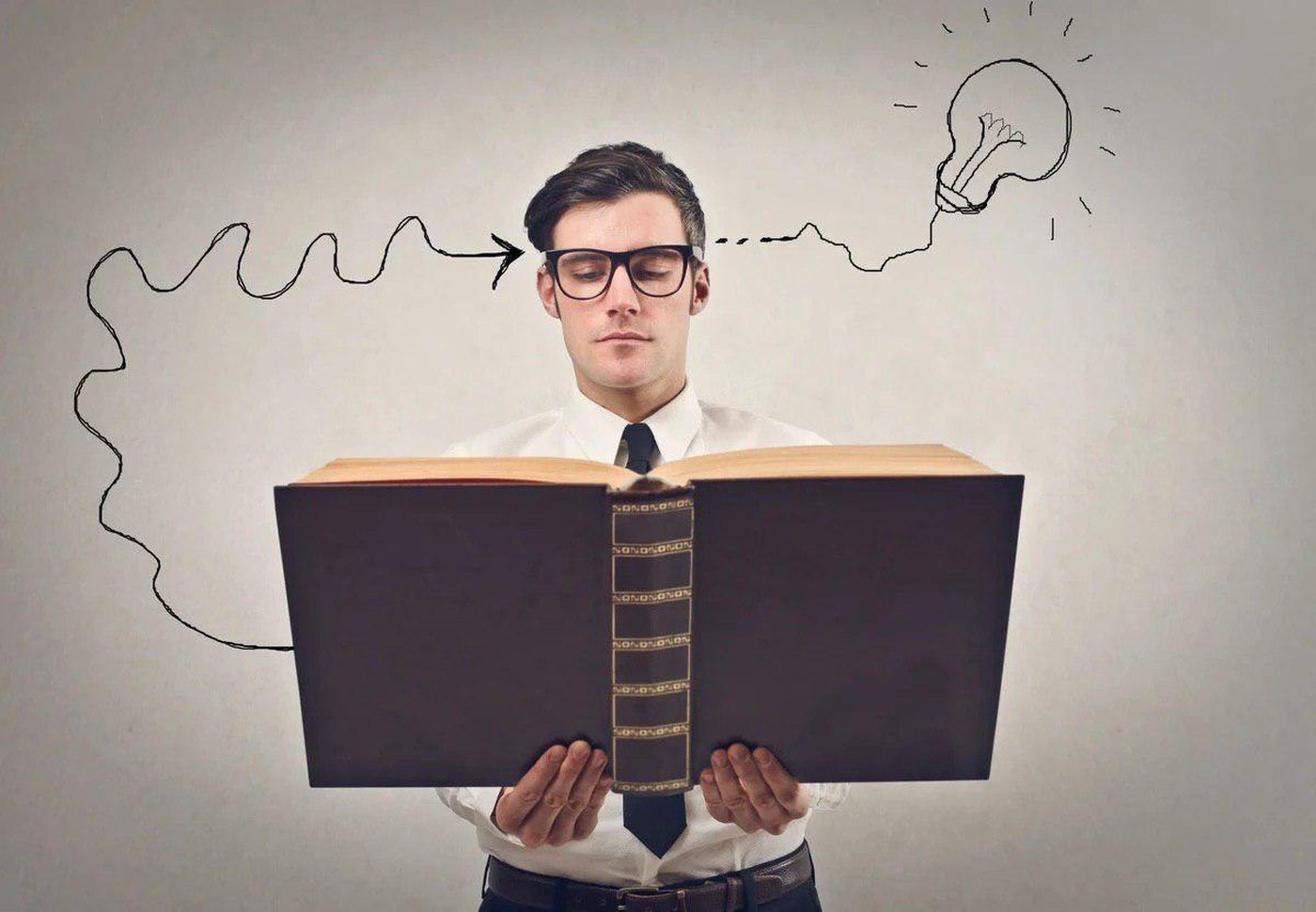 A reader at an open book, with a drawn line running from the page to a lightbulb above his head
